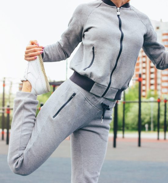 Attractive fit young woman in grey sport wear the doing warm up stretching before training on the street workout area. The healthy lifestyle in city concept