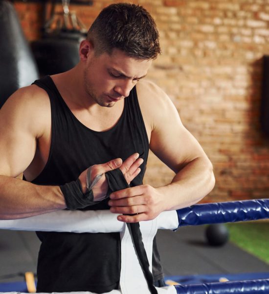 Young boxer in sportive clothes have practice in the gym.